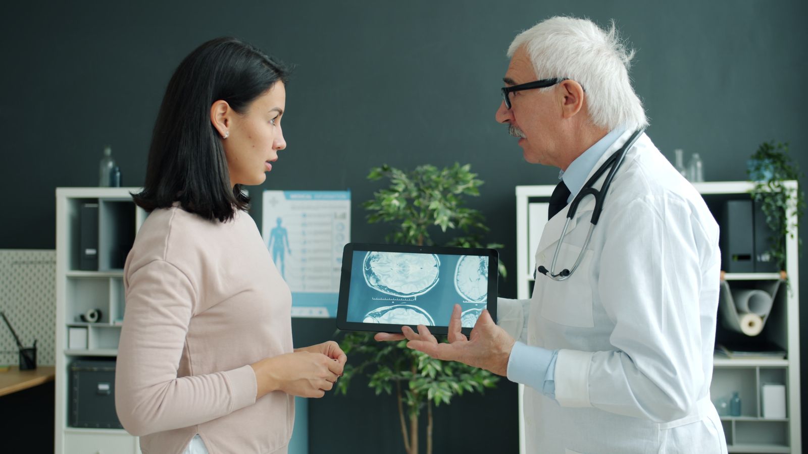 A clinician showing scan images to an adult in a medical office