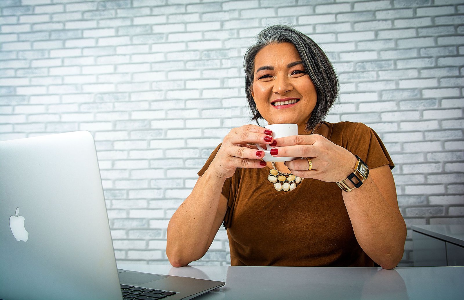 A smiling woman holding coffee at a desk