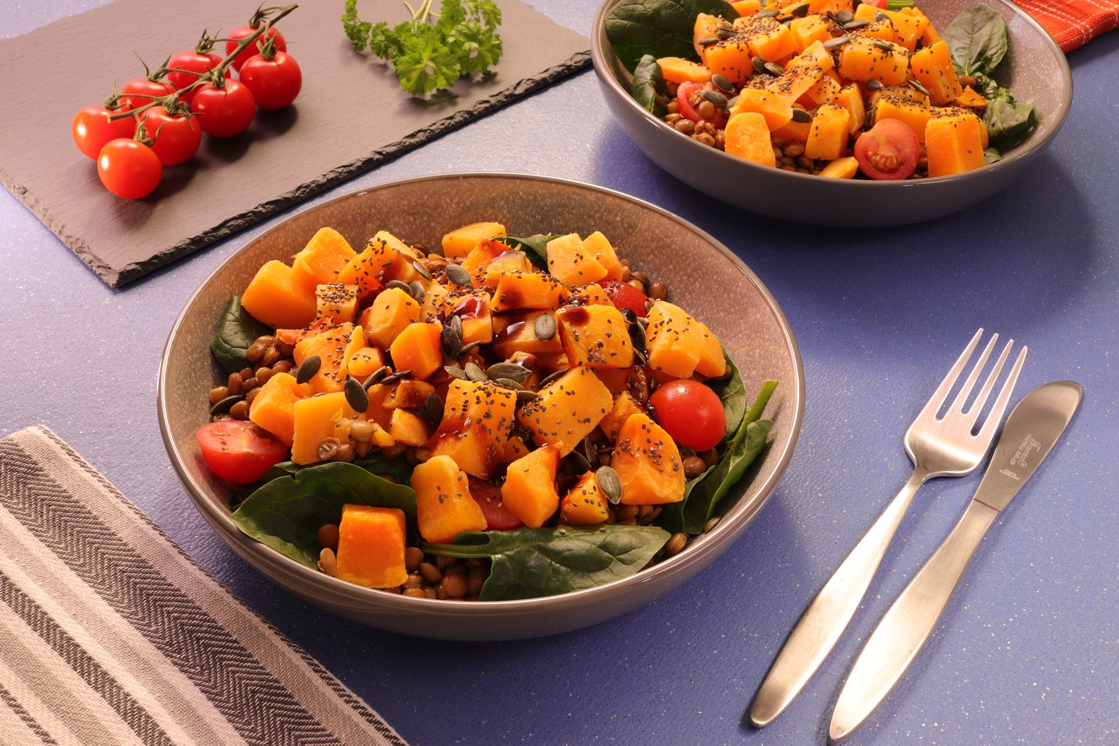 A bowl of lentils, roasted squash, cherry tomatoes, and herbs