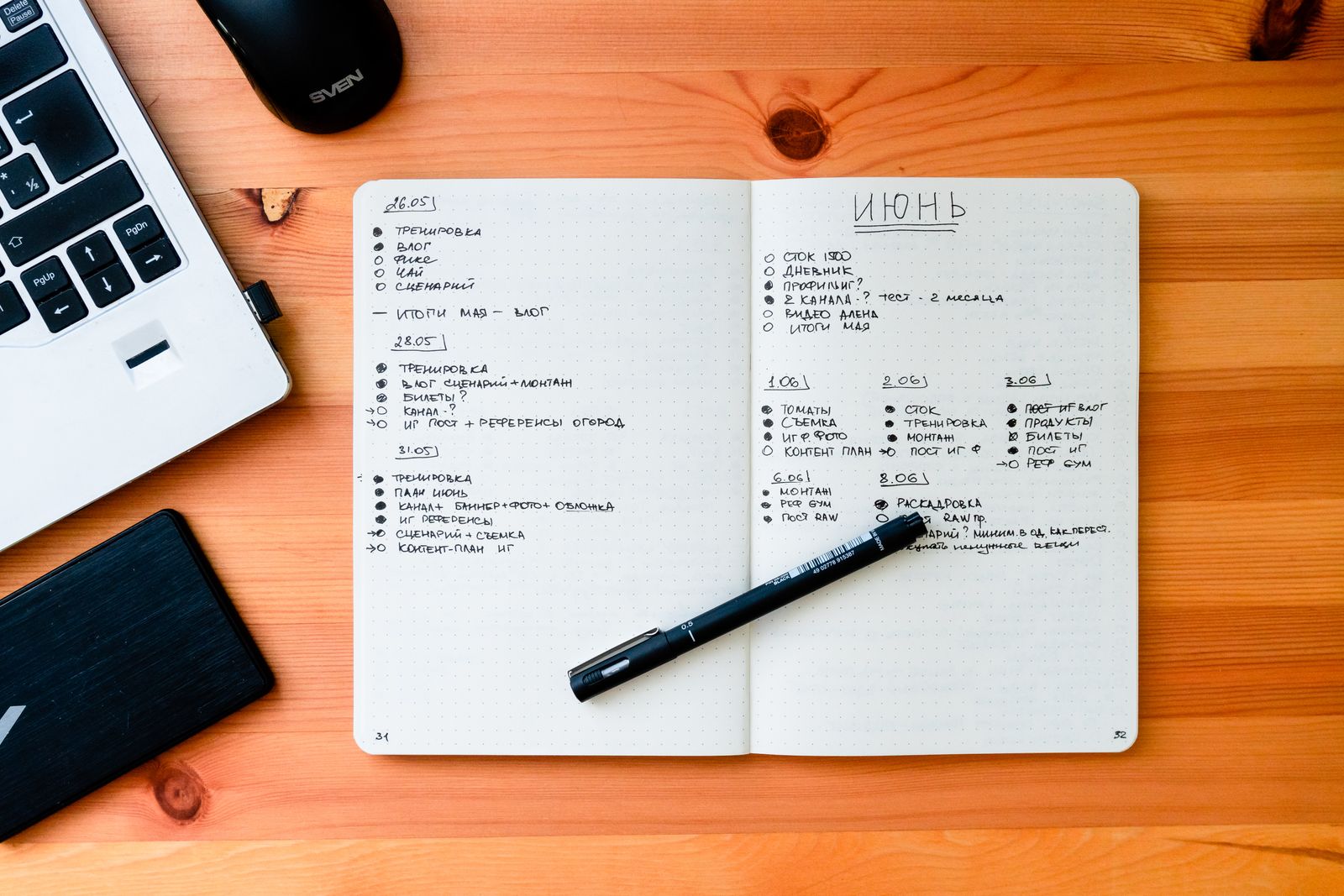 A notebook and pen beside a laptop on a desk