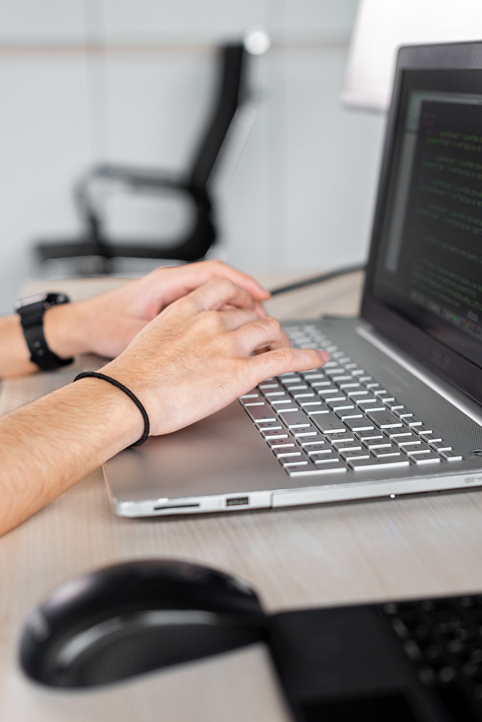 Hands working on a laptop in an office