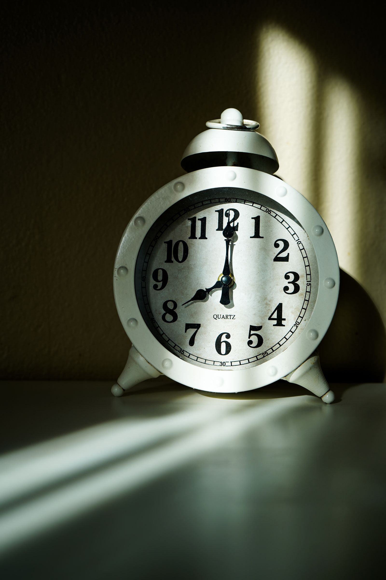 A close-up of a white vintage alarm clock face in warm light