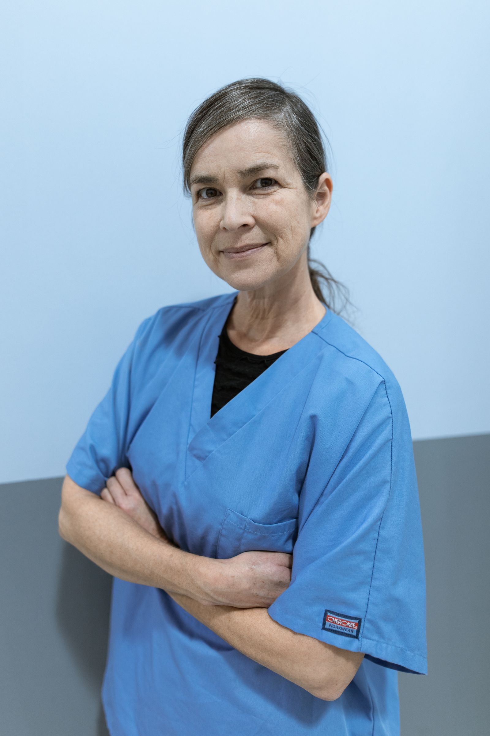 A clinician in blue scrubs smiling toward the camera