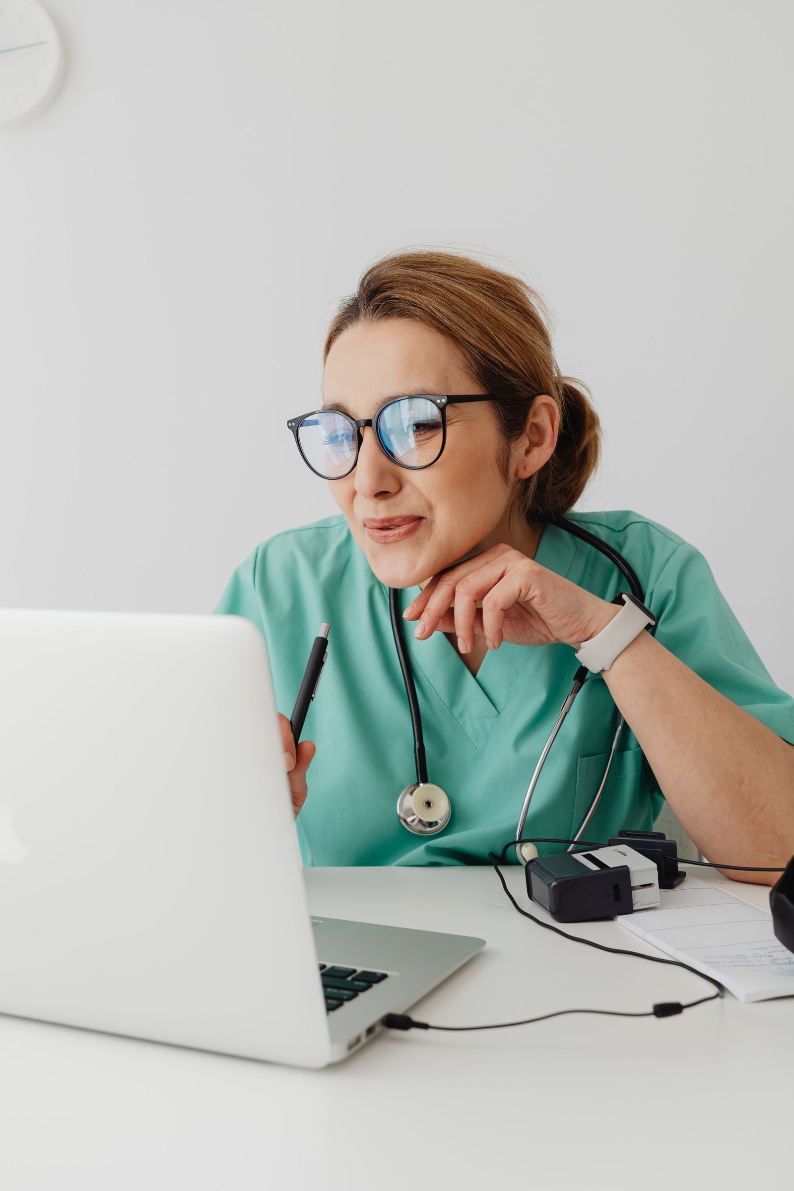 A clinician with a stethoscope using a laptop